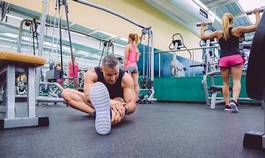 Plakat man stretching and women doing dumbbells exercises in gym