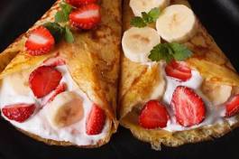 Obraz na płótnie crepes with strawberries, bananas and cream close-up. horizontal