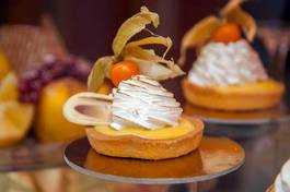 Fotoroleta cakes with meringue and berries of cape gooseberry on a show-window of shop