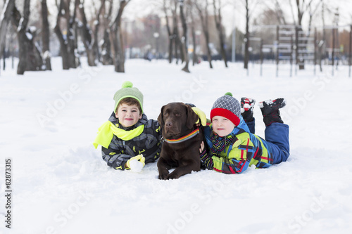 Obraz na płótnie Dzieciaki bawią się z psem na śniegu