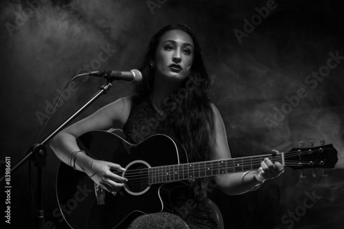 Naklejka Beautiful young lady playing acoustic guitar