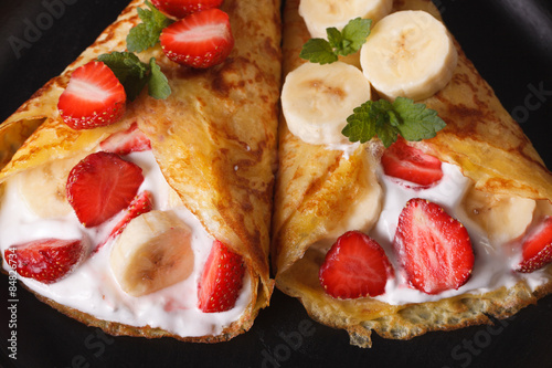 Plakat crepes with strawberries, bananas and cream close-up. horizontal