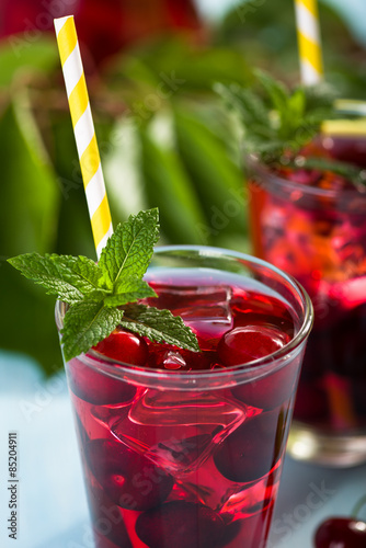 Naklejka Glass of cherry juice on blue wooden table