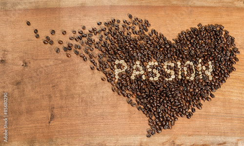 Fototapeta Cuore di chicchi di caffè su un piano di legno grezzo.