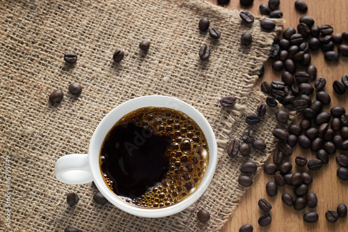 Fotoroleta Coffee cup with bubbles and beans on a sack background, top view