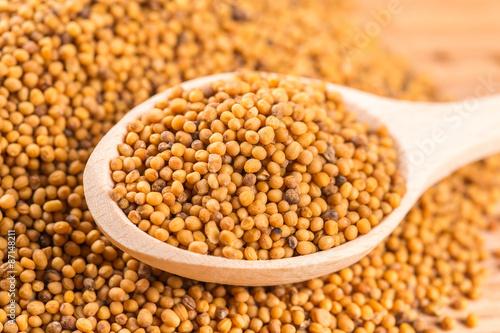 Naklejka Wooden spoon of mustard seeds on wood table