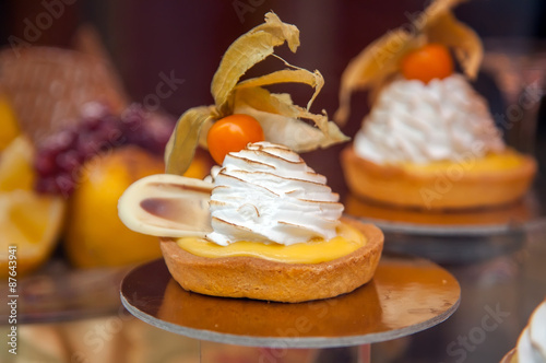 Fotoroleta Cakes with meringue and berries of cape gooseberry on a show-window of shop